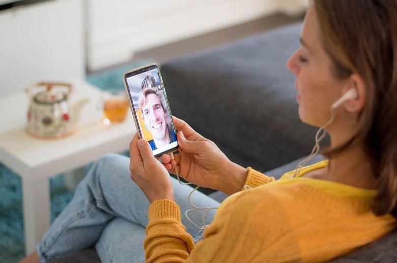 Mulher fazendo chamada de vídeo com um homem através de um smartphone